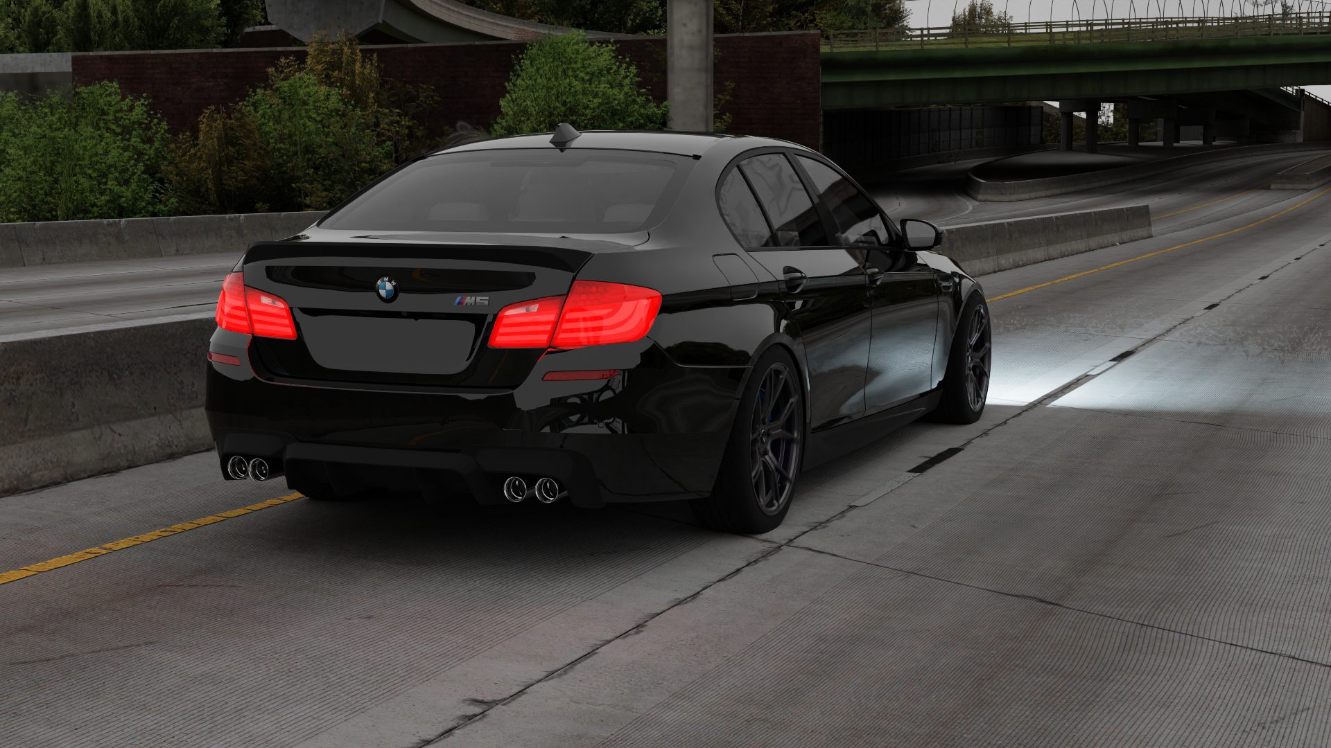 Black sports sedan driving on a concrete highway under an overpass